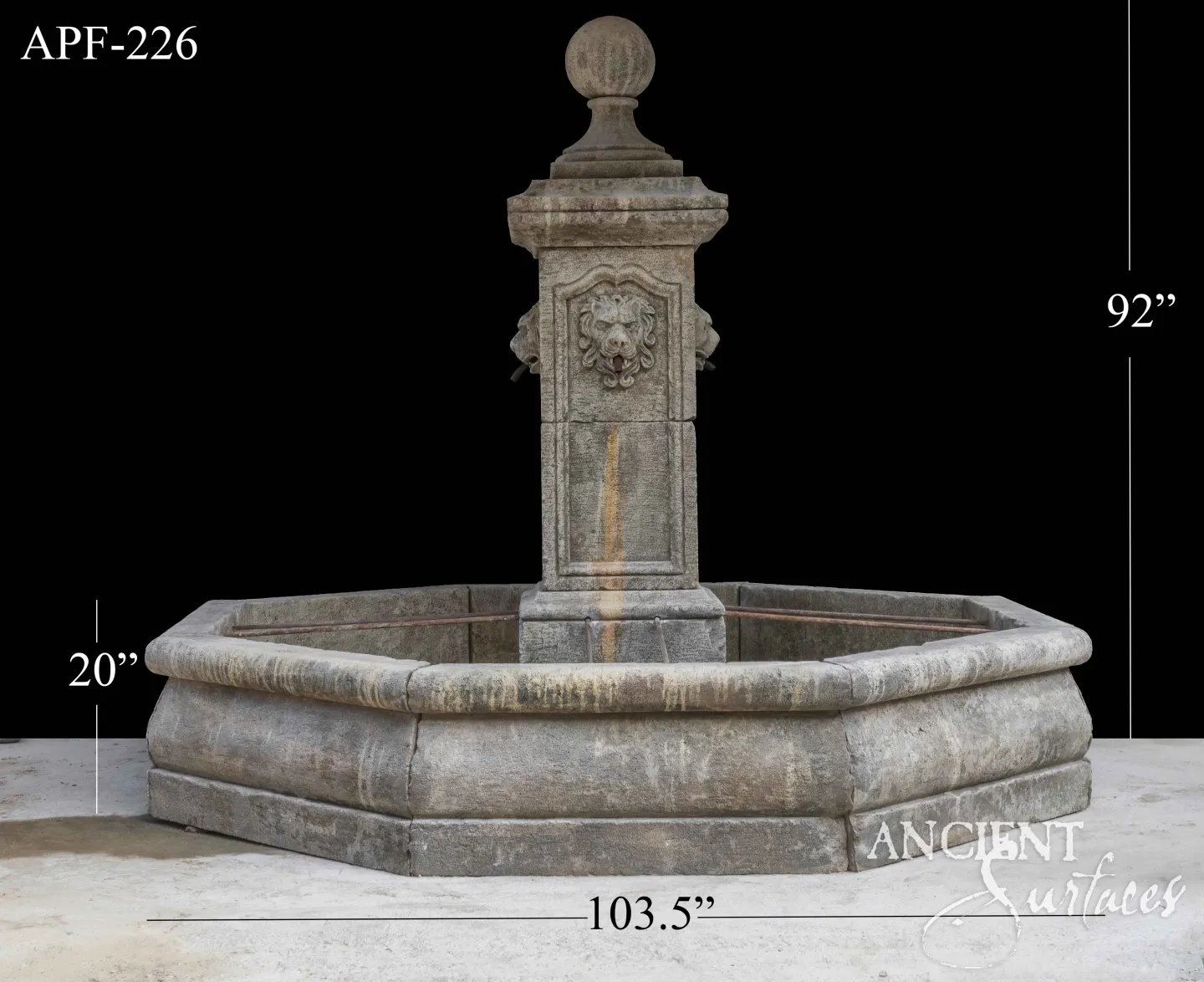 Tall reclaimed limestone pool fountain with a carved lion-mask panel on the column